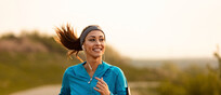 Happy female runner jogging in the morning in nature.