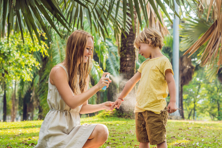 Una mamma spruzza spray anti insetti al figlio foto iStock. - RIPRODUZIONE RISERVATA