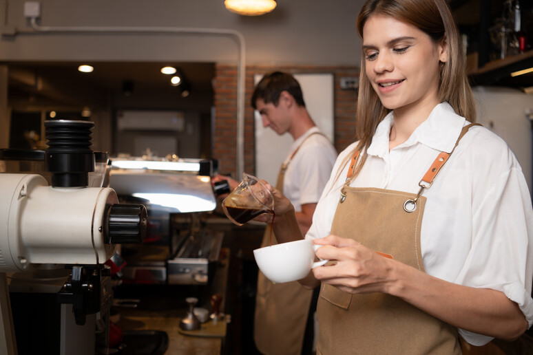 Una giovane barista prepara un cappuccino foto iStock. - RIPRODUZIONE RISERVATA